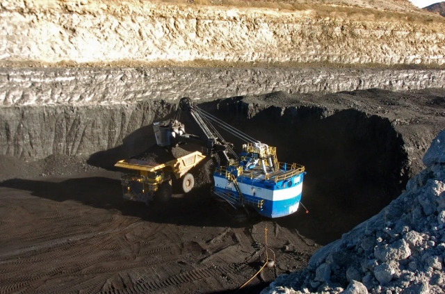 A coal truck being loaded into a pit, ready for transportation.