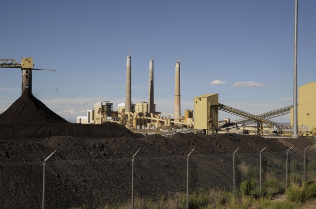 A coal plant visible in the distance, emitting smoke into the sky.