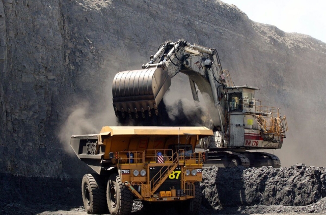 A massive dump truck drives through a coal mine, transporting materials for mining operations.